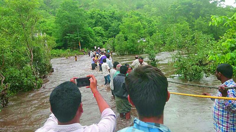 People cross a river with the help of a rope in Markapuram as heavy rains lash Prakasam district on Wednesday. (Photo: DC) People cross a river with the help of a rope in Markapuram as heavy rains lash Prakasam district on Wednesday. (Photo: DC)