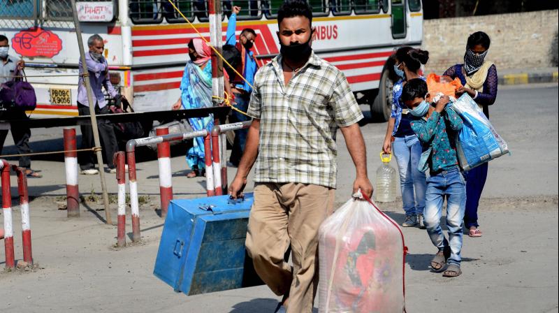 Migrants walk to board a train to their homes in UP, during the ongoing COVID-19 nationwide lockdown, in Jalandhar, Monday. PTI Photo