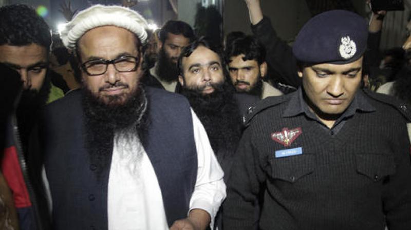 A Pakistani police officer escorts Hafiz Saeed, Chief of Pakistan's religious group Jamaat-ud-Dawa outside party's headquarters in Lahore. (Photo: AP) A Pakistani police officer escorts Hafiz Saeed, Chief of Pakistan's religious group Jamaat-ud-Dawa outside party's headquarters in Lahore. (Photo: AP)