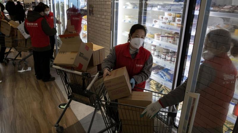 Workers at the 7Fresh supermarket restock the fridge in Beijing. Stores that offer online purchases are enjoying brisk sales as residents avoid going out during the current viral outbreak with authorities last week requiring people returning to the capital to self-quarantine at home or in a concentrated area for medical observation.AP photo