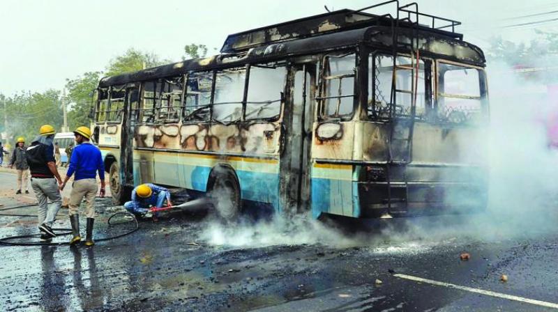 Firefighters and policemen try to douse a fire after activists of the Karni Sena torched a Haryana Roadways bus during a demonstration against the release of Padmaavat in Gurgaon. (Photo: PTI) Firefighters and policemen try to douse a fire after activists of the Karni Sena torched a Haryana Roadways bus during a demonstration against the release of Padmaavat in Gurgaon. (Photo: PTI)