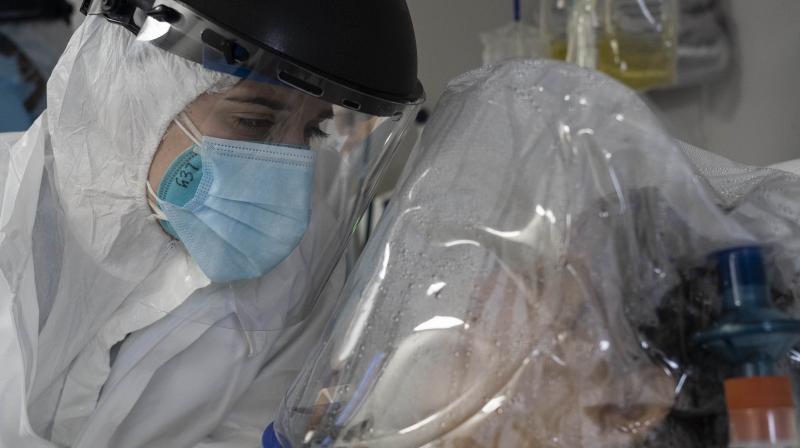 A member of the medical staff speaks to a patient who is treated with a helmet-based ventilator in the COVID-19 intensive care unit at the United Memorial Medical Center on July 28, 2020 in Houston, Texas. (AFP)