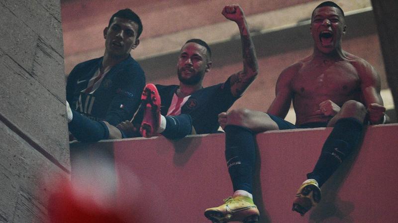 Paris Saint-Germains Brazilian forward Neymar (C) and teammate Kylian Mbappe (R) celebrate with supporters outside the Parc des Princes stadium, in Paris, on Wednesday, after winning the UEFA Champions League round of 16 second leg match against Borussia Dortmund held behind closed doors. AFP Photo