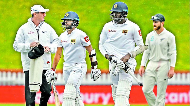 Sri Lanka batsmen Kusal Mendis and Angelo Mathews walk off the field as rain stops play. — AP Sri Lanka batsmen Kusal Mendis and Angelo Mathews walk off the field as rain stops play. — AP