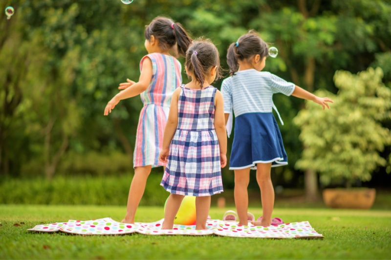 sisters children playing bubbles during a picnic at the park