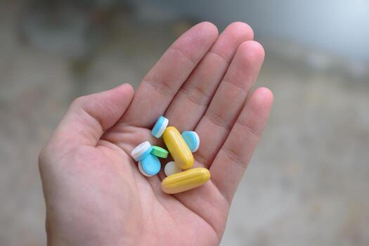 many pills and colors on hand top view and close up in blurred background for concept of medicine for treating disease or nourishing the body photo
