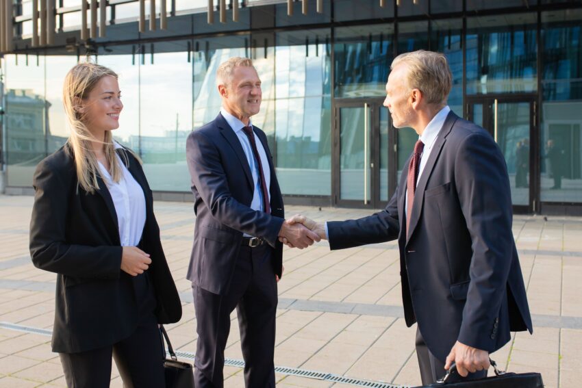 positive business partners meeting office building shaking hands with each other side view medium shot corporate communication handshake concept 1