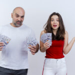 impressed adult couple woman showing empty hand both holding money looking