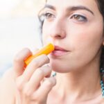 close up young woman applying lip balm 23 2147893527