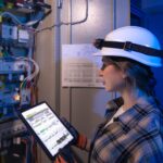 woman electrician checks switchboard with tablet electrical inspection