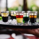 side view hand holding tray with ice colorful cocktails shot glasses 141793 3015