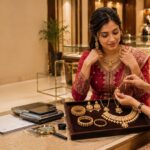 Indian woman comparing gold jewellery with a female consultant in a luxury jewellery showroom with a jewellery tray weighing scale and magnifying glass on the table