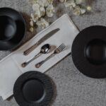 top view table setting gey surface with empty black plates silver spoon fork knife 140725 12953