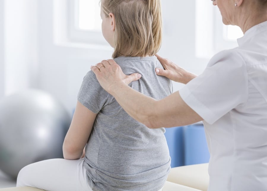 Physiotherapist massaging a girl with spine deformity - paediatric physiotherapy centres for kids in Singapore