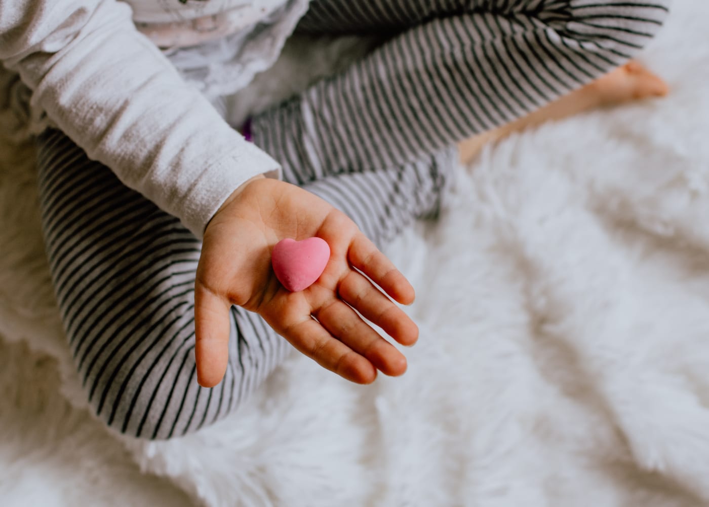 heart shaped stone on a kids hand for parenting during covid