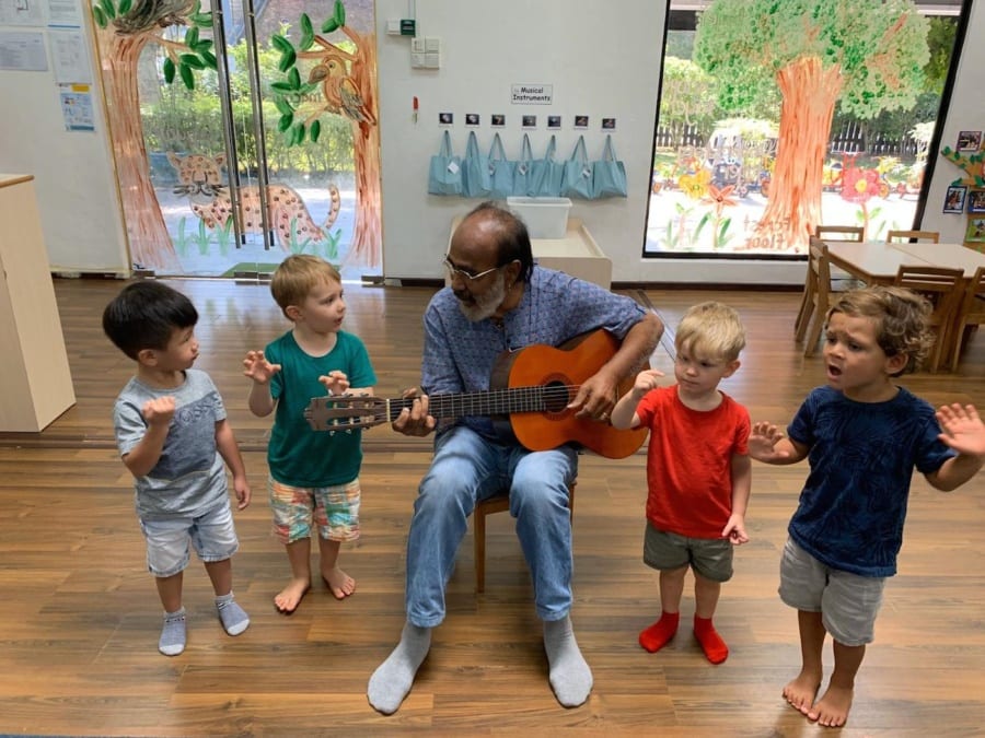 Teacjer playing guitar and singing with children | White Lodge International Preschool & Childcare