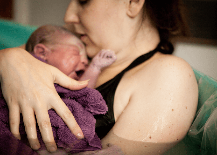 The truth about natural childbirth woman with newborn baby water birth