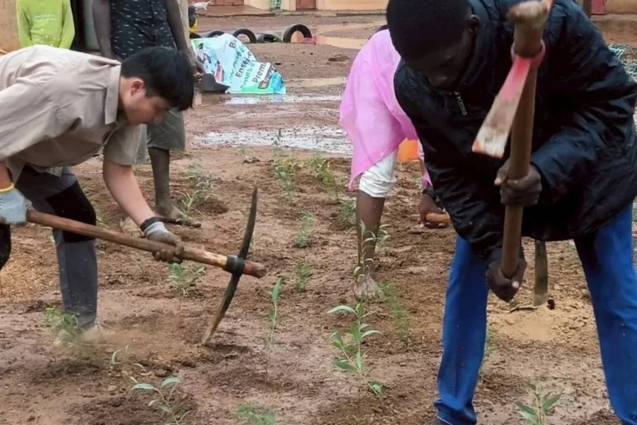 當地居民與逢甲學生攜手揮動鋤頭，在非洲土地上共同耕耘綠色希望的未來。