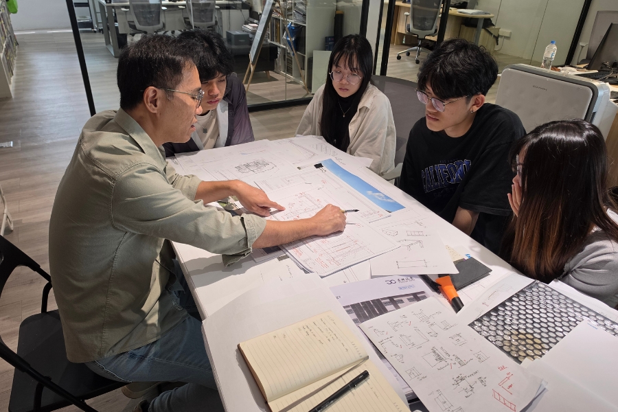 主持建築師與四位實習生討論設計。