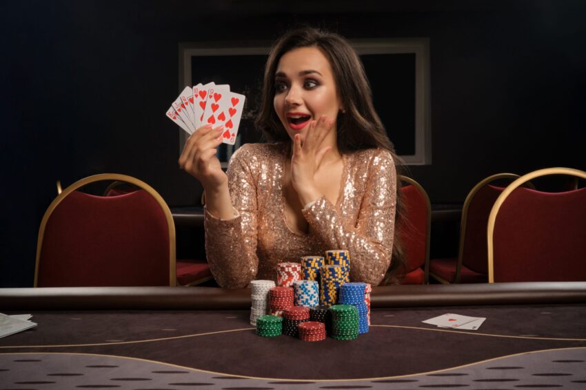 happy brunette girl brilliant gold dress is playing poker sitting table casino she is making bets waiting big win showing her cards gambling money games fortune scaled 2