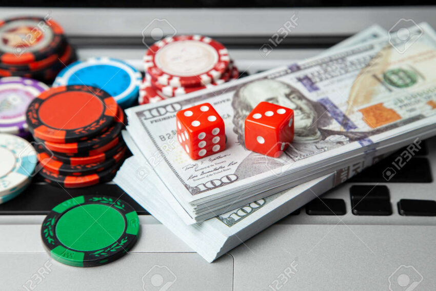 114238778 online casino laptop laptop keyboard and chips with dice and money cash dollars on green gaming