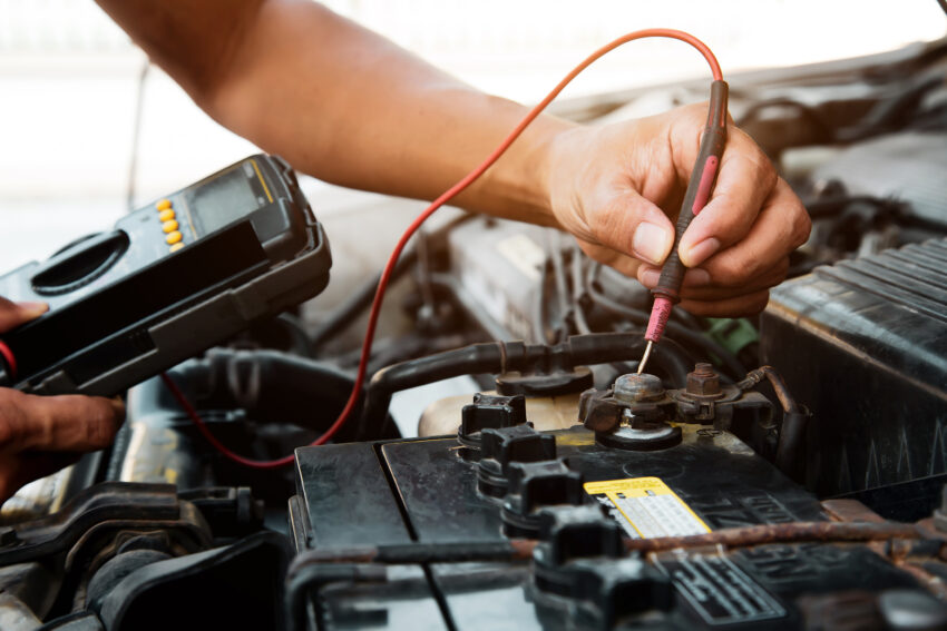 auto mechanic using measuring equipment tool checking car battery