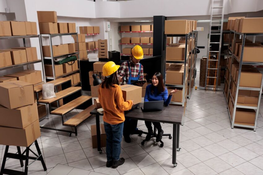 warehouse package handlers doing inventory control while coworking with logistics manager asian storehouse employees scanning cardboard box creating invoice laptop