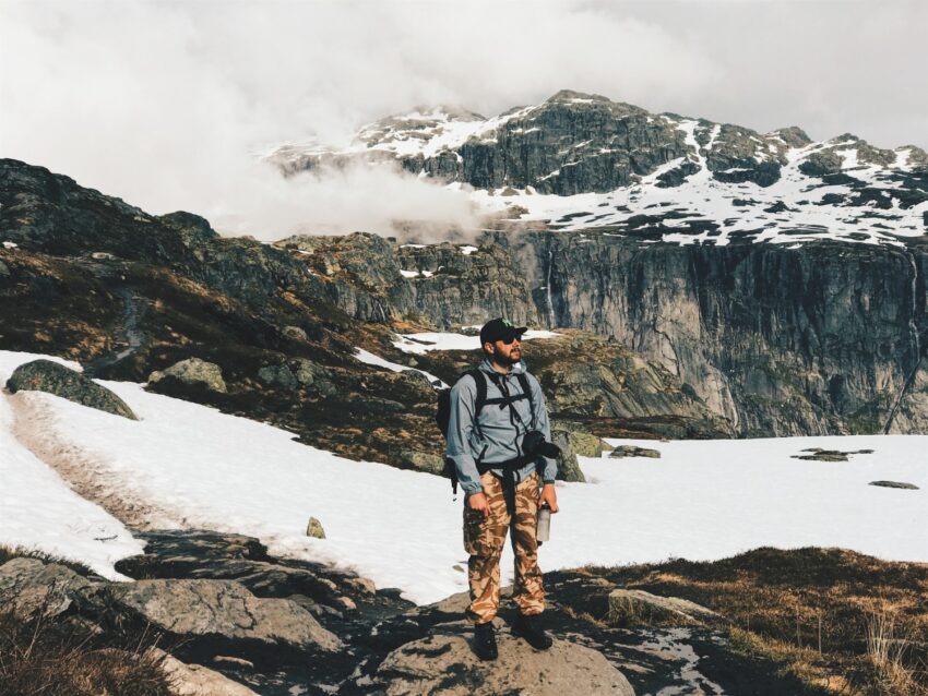 man with camera rucksack stands before mountains covered with snow 2mb