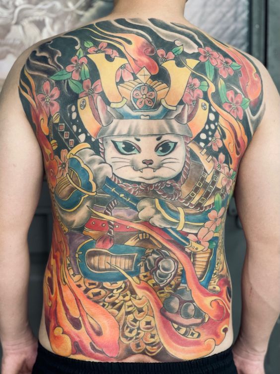 Hình xăm chiến binh mèo samurai đặt trên đống vàng kín lưng Hình xăm trên lưng với hình ảnh mèo samurai, hoa anh đào và lửa, màu sắc tươi sáng và chi tiết phức tạp.