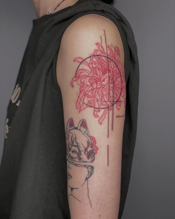 H&igrave;nh xăm tr&ecirc;n c&aacute;nh tay với hoa văn đỏ v&agrave; đen, bao gồm hoa v&agrave; khu&ocirc;n mặt người đeo mặt nạ.