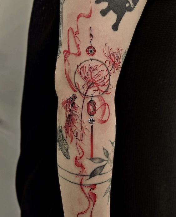 H&igrave;nh xăm tr&ecirc;n c&aacute;nh tay với hoa văn c&aacute; v&agrave; hoa m&agrave;u đỏ, kết hợp c&aacute;c chi tiết h&igrave;nh học v&agrave; nghệ thuật.