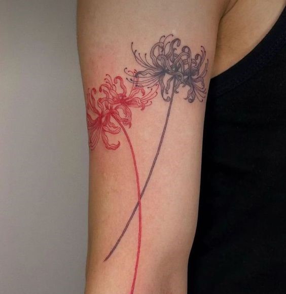 H&igrave;nh xăm hai b&ocirc;ng hoa m&agrave;u đỏ v&agrave; đen tr&ecirc;n c&aacute;nh tay người mặc &aacute;o kh&ocirc;ng tay m&agrave;u đen.