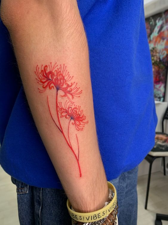 H&igrave;nh xăm hoa đỏ tr&ecirc;n c&aacute;nh tay người mặc &aacute;o xanh, đeo v&ograve;ng tay m&agrave;u v&agrave;ng.