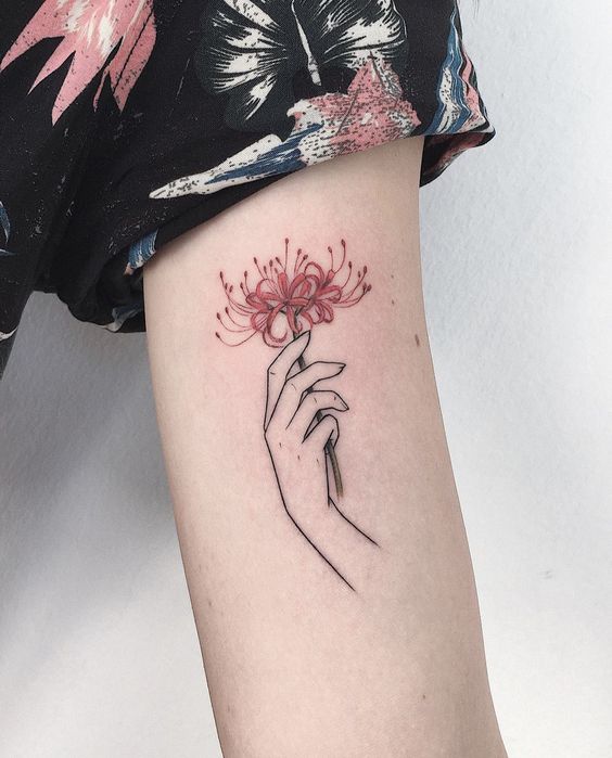 H&igrave;nh xăm tr&ecirc;n c&aacute;nh tay với h&igrave;nh b&agrave;n tay cầm hoa m&agrave;u đỏ, &aacute;o họa tiết bướm v&agrave; hoa.