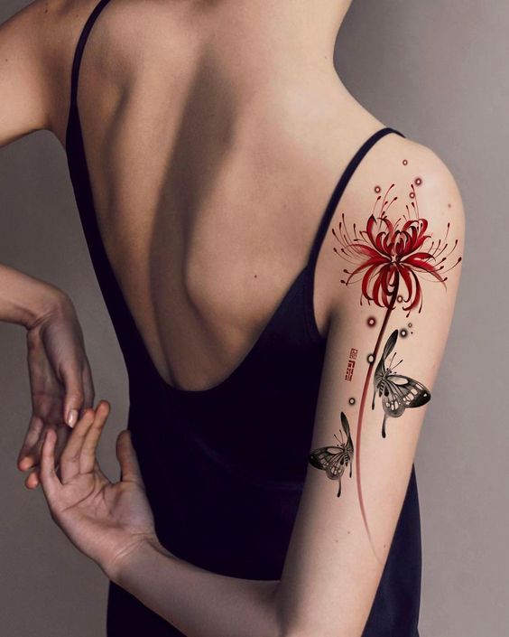 Người mặc v&aacute;y đen hở lưng với h&igrave;nh xăm hoa v&agrave; bướm m&agrave;u đỏ tr&ecirc;n c&aacute;nh tay.