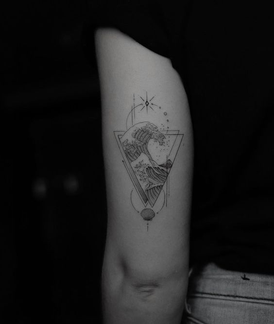 H&igrave;nh xăm tr&ecirc;n c&aacute;nh tay, thiết kế s&oacute;ng biển trong tam gi&aacute;c, k&egrave;m họa tiết sao v&agrave; vỏ s&ograve;.