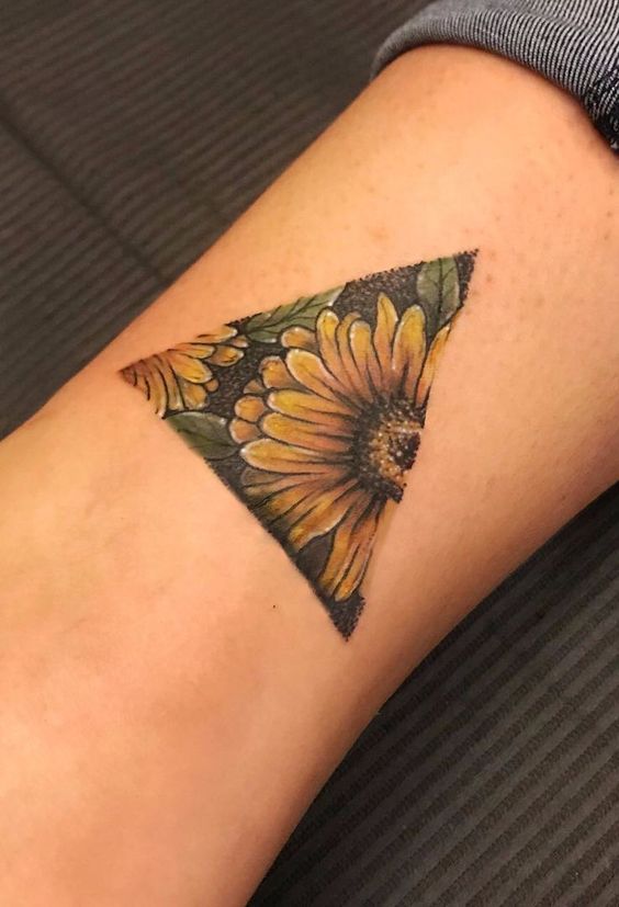 H&igrave;nh xăm tr&ecirc;n c&aacute;nh tay với thiết kế hoa hướng dương trong khung tam gi&aacute;c, m&agrave;u sắc tươi s&aacute;ng v&agrave; chi tiết.