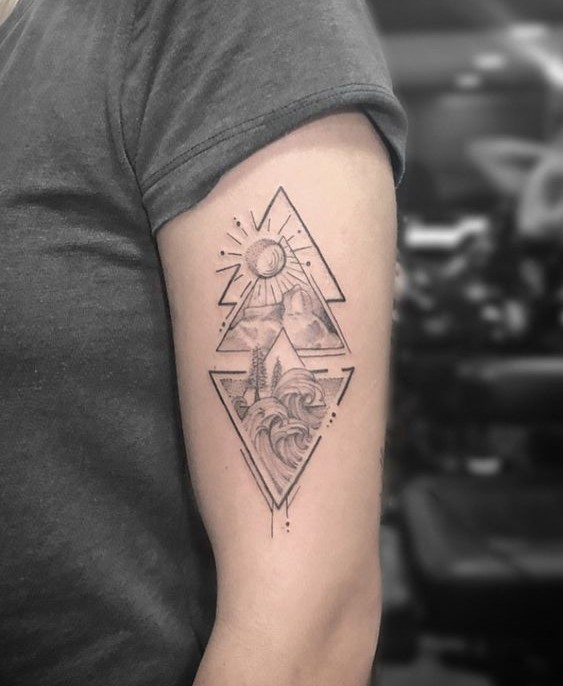 H&igrave;nh xăm tr&ecirc;n c&aacute;nh tay với họa tiết h&igrave;nh học gồm mặt trời, n&uacute;i v&agrave; s&oacute;ng biển.