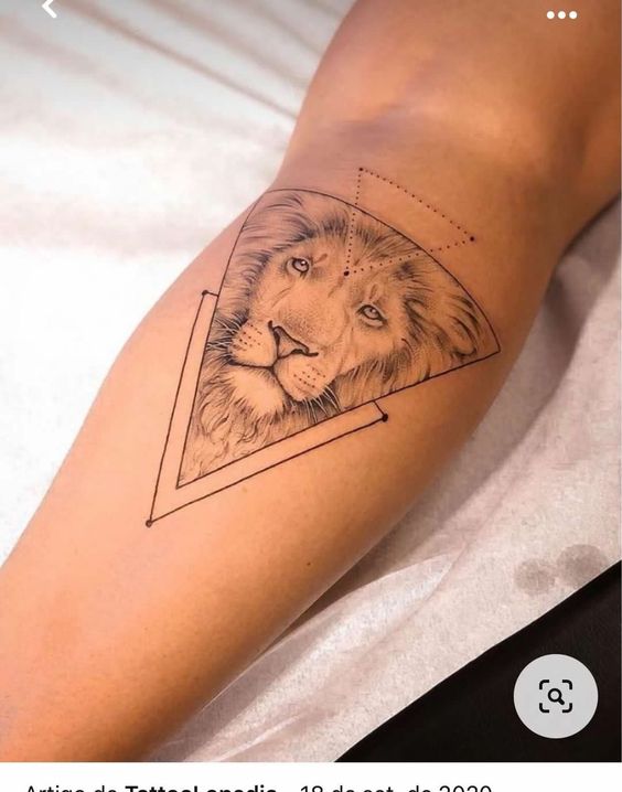H&igrave;nh xăm đầu sư tử trong khung tam gi&aacute;c, tr&ecirc;n bắp ch&acirc;n người, với c&aacute;c chi tiết h&igrave;nh học xung quanh.