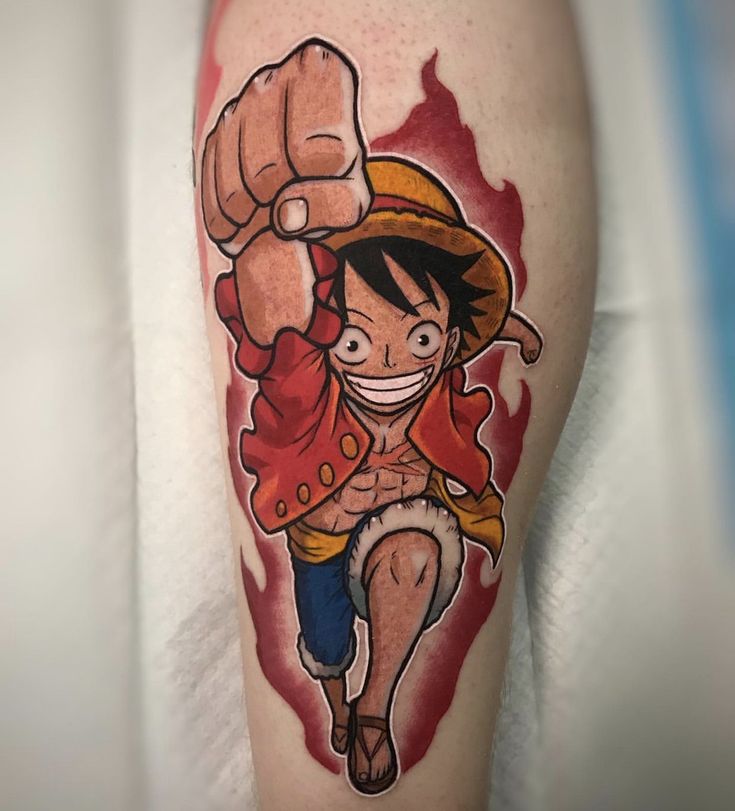 hình xăm nhân vật one piece được thiết kế có màu Hình xăm nhân vật hoạt hình với nắm đấm đưa về phía trước, áo đỏ và mũ rơm trên nền lửa.