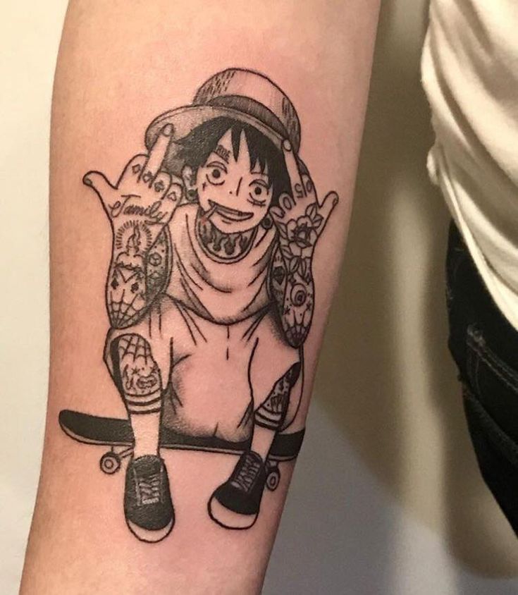 nhân vật chính luffy one piece Hình xăm trên cánh tay với nhân vật hoạt hình đội mũ, ngồi trên ván trượt, tay có nhiều hình xăm nhỏ.