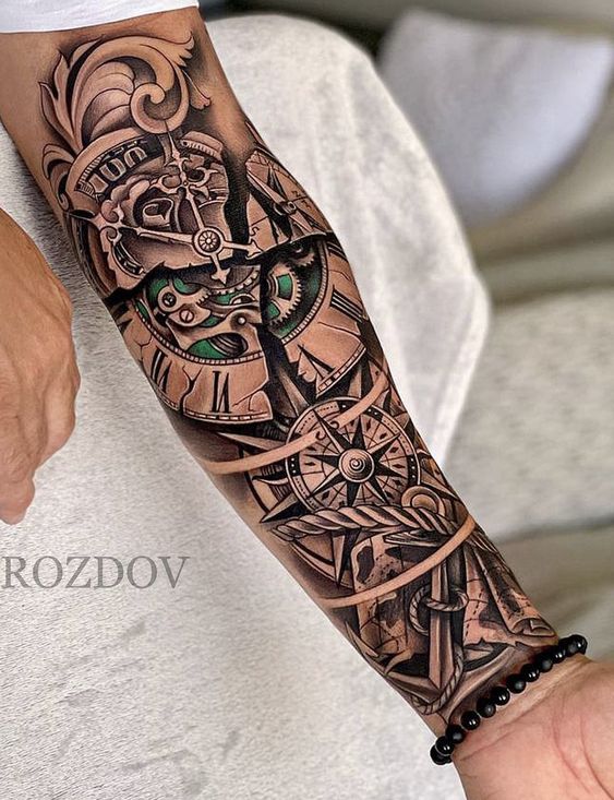 Hình xăm trên cánh tay với thiết kế la bàn và bánh răng phức tạp, chi tiết và nghệ thuật.