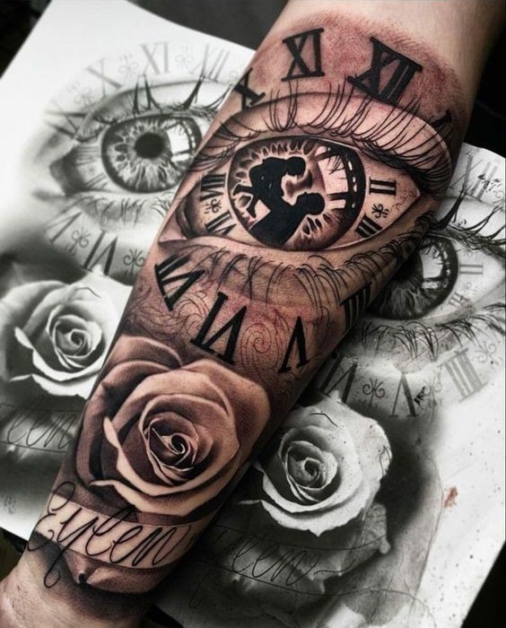 Hình xăm trên cánh tay với hình ảnh mắt, đồng hồ La Mã và hoa hồng, nền là bản vẽ phác thảo.