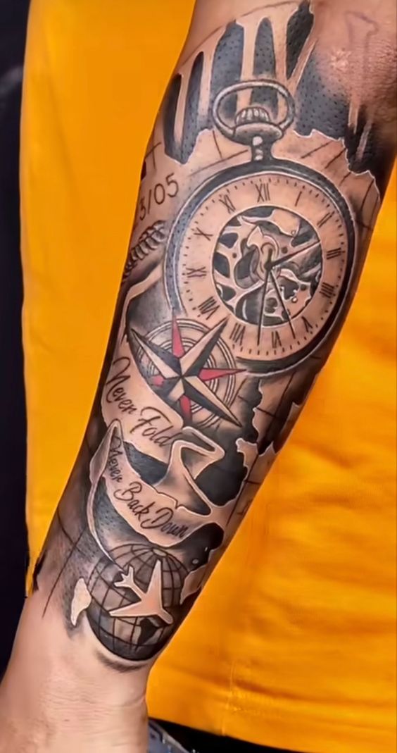Hình xăm trên cánh tay với hình đồng hồ, la bàn và dòng chữ, nền áo màu vàng.