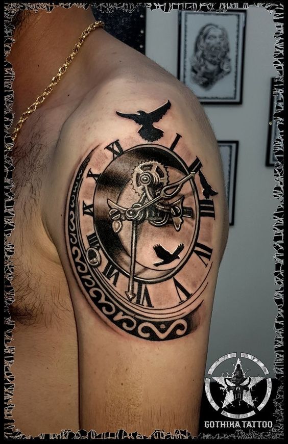 Hình xăm trên vai mô tả đồng hồ với số La Mã và hình chim bay, nền có các bức tranh khác.