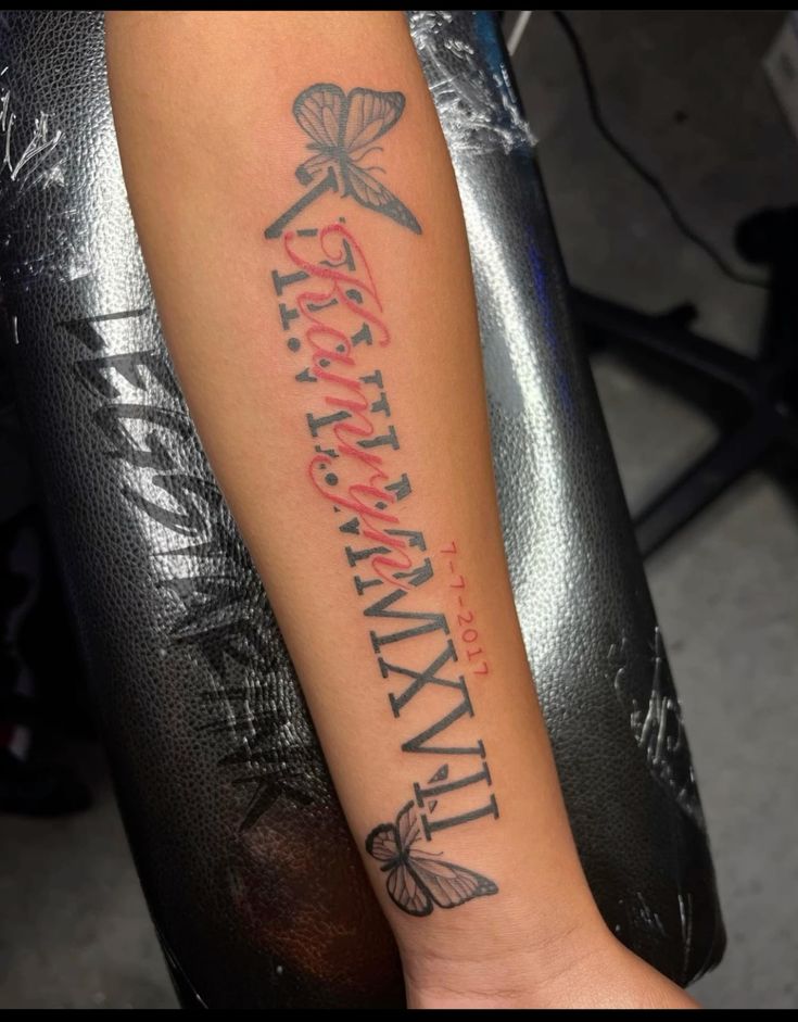 Hình xăm trên cánh tay với chữ số La Mã và hình con bướm.