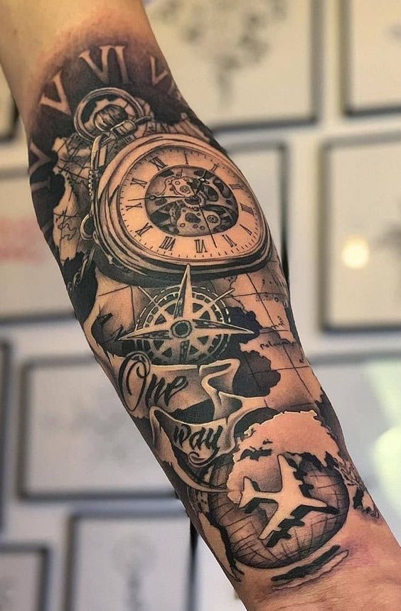 Hình xăm trên cánh tay với đồng hồ cổ, la bàn, máy bay và bản đồ thế giới, kèm chữ "One way".