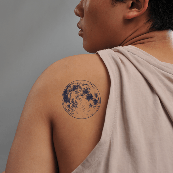 1_1__17__9f8004164bd34b2384acb5ab1618cb62_grande Người mặc áo không tay, vai có hình xăm tròn màu xanh đen.