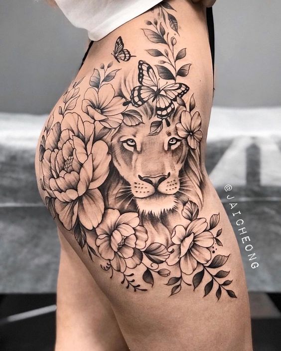 f9314354ee9193221ea73f49b2d498bc Hình xăm hoa và sư tử trên lưng người, với bươm bướm và lá trang trí xung quanh.