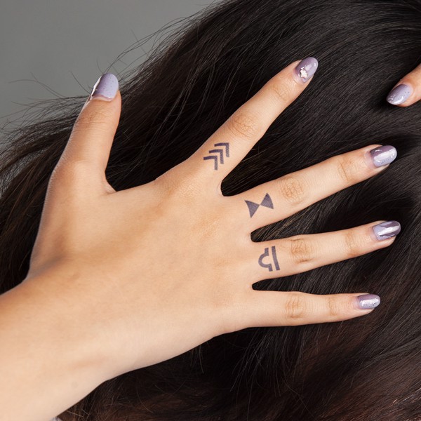 B&agrave;n tay với m&oacute;ng tay sơn m&agrave;u t&iacute;m v&agrave; h&igrave;nh xăm nhỏ tr&ecirc;n c&aacute;c ng&oacute;n tay, chạm v&agrave;o t&oacute;c d&agrave;i m&agrave;u đen.